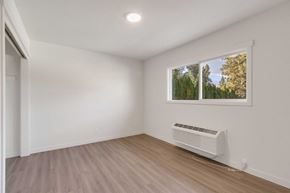 Coeur D'alene apartment for rent - A room with a window showing trees and a white air conditioner on the floor.