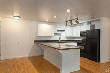 Spokane apartment for rent - A kitchen with a black refrigerator and white cabinets.