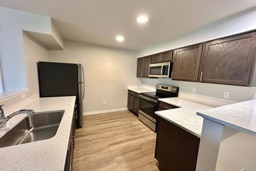 Post Falls apartment for rent - A kitchen with wooden cabinets and a black fridge.