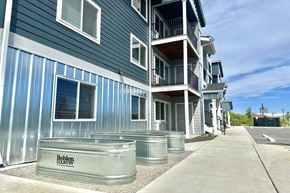 Post Falls apartment for rent - A blue and silver building with the words "Behling Country" on a planter in front.