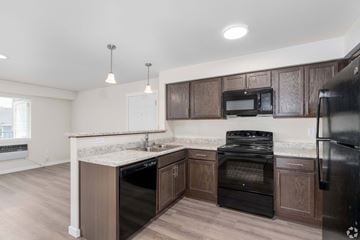 Spokane apartment for rent - A kitchen with dark wood cabinets and black appliances.
