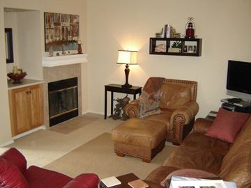 Spokane Valley apartment for rent - A living room with a fireplace, two chairs, a coffee table, and a painting on the wall.