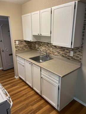 Burnaby apartment for rent - a kitchen with white cabinets and a wooden floor
