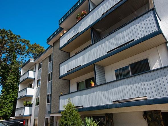Esquimalt apartment for rent - an apartment building with balconies and a blue sky in the background