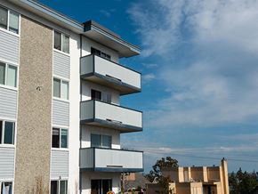 Esquimalt apartment for rent - a white apartment building with balconies against a blue sky