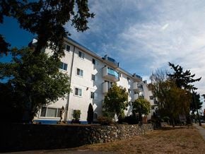 Esquimalt apartment for rent - a white apartment building with trees in front of it
