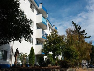 Esquimalt apartment for rent - A white building with blue trim and balconies.