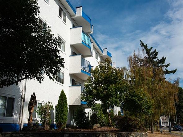 Esquimalt apartment for rent - a white apartment building with blue balconies