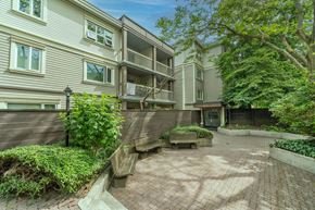 Vancouver apartment for rent - A courtyard surrounded by apartment buildings with a bench and a tree.