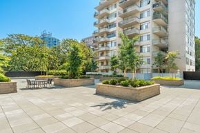 Vancouver apartment for rent - A sunny day at a courtyard with a table and chairs surrounded by trees and plants.