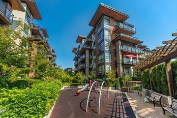 North Vancouver apartment for rent - A playground with a slide and a climbing frame is situated in a courtyard surrounded by residential buildings.