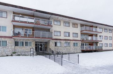 Burnaby apartment for rent - A large building with balconies and a black fence in front.
