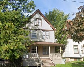 Milwaukee apartment for rent - A house with a grey siding and a brown roof with a white window and a door.