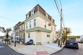 Philadelphia apartment for rent - A three-story building with a beige and green facade sits on a street corner.