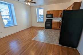 Philadelphia apartment for rent - an empty living room and kitchen with wood floors and a black refrigerator