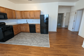 Philadelphia apartment for rent - an empty kitchen with wood floors and a black refrigerator
