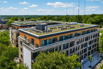 Philadelphia apartment for rent - A modern building with a green roof is surrounded by trees.