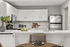 Redmond condo for rent - a kitchen with white cabinets and a table and a refrigerator