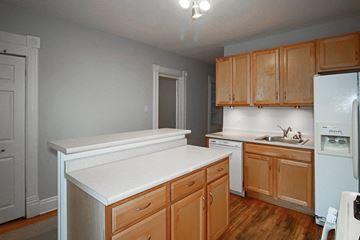 Chicago apartment for rent - an empty kitchen with wooden cabinets and a white counter top