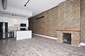 Chicago apartment for rent - an empty living room with a brick wall and a fireplace