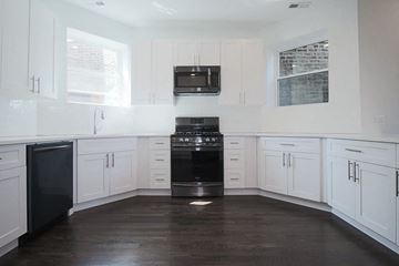 Chicago apartment for rent - a kitchen with white cabinets and a stove and a microwave