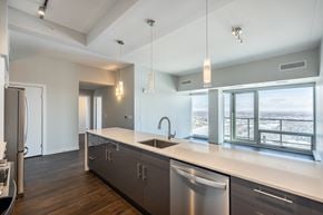Winnipeg apartment for rent - A modern kitchen with a stainless steel dishwasher and a large window overlooking the city.