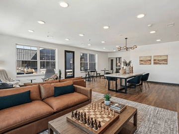 Warsaw apartment for rent - A living room with a brown leather couch and a chess board on the coffee table.