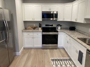 Laconia apartment for rent - a white kitchen with stainless steel appliances and white cabinets