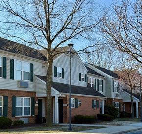 Bridgeville apartment for rent - A tree stands in front of a grey house with green shutters.
