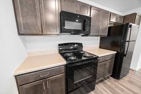 Cedar Rapids apartment for rent - a kitchen with dark wood cabinets and black appliances  at Union at Wiley, Iowa, 52404