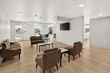 Des Moines apartment for rent - A living room with brown chairs and a black TV mounted on the wall.