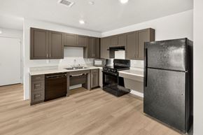 Des Moines apartment for rent - A black refrigerator stands in a kitchen with wooden floors and white walls.