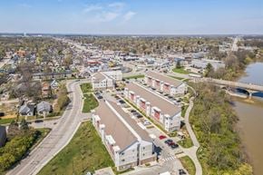 Indianapolis apartment for rent - A river flows through a town with apartment buildings on the right at Union at 16th, Indianapolis, IN