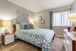 Lakewood apartment for rent - A bedroom with a bed, nightstand, and window at The Ranch at Bear Creek Apartments, Lakewood, CO