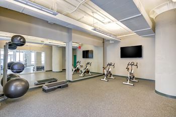 A gym with a mirror, exercise bikes, and a television.