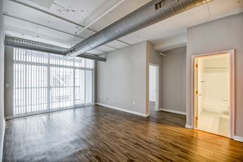 A room with wooden floors and a large window with blinds.