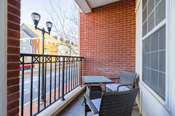 A patio with a black metal railing, a small table and chairs, and a brick wall at harbor pointe in bayonne, new jersey.