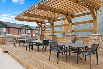 A wooden deck with a table and chairs under a pergola.