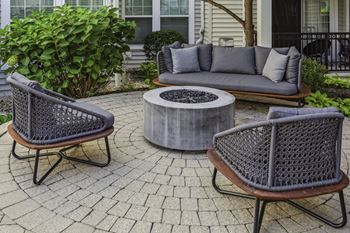 A stone patio with chairs and a fire pit