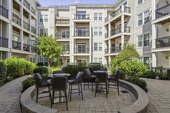 A patio with tables and chairs in front of an apartment building