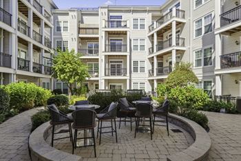 A patio with tables and chairs in front of an apartment building