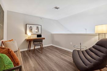 A living room with a couch and a chair and a desk
