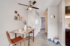 Lakewood apartment for rent - A dining room with a brown chair and a table with a vase of flowers on it at Mountain Vista Apartments, Lakewood