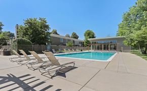 Lakewood apartment for rent - A pool with chairs around it and a building in the background at The Ranch at Bear Creek Apartments, Colorado, 80227