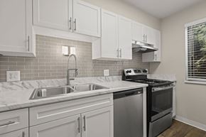 Lakewood apartment for rent - A kitchen with white cabinets and a stainless steel dishwasher at The Ranch at Bear Creek Apartments, Lakewood