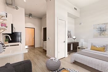 A modern bedroom with a large bed and a kitchen area.