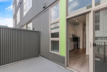 A modern house with a grey exterior and a glass door leading to the interior.