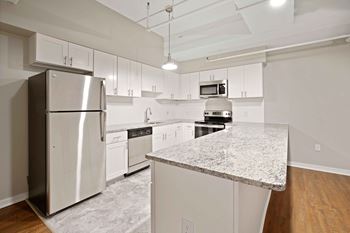 A kitchen with a granite counter top and stainless steel appliances.
