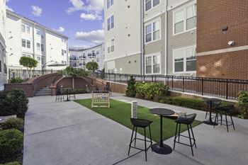 An outdoor patio with tables and chairs in front of apartment buildings