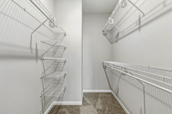 The closet of a bedroom with metal shelves and a mirrored wall